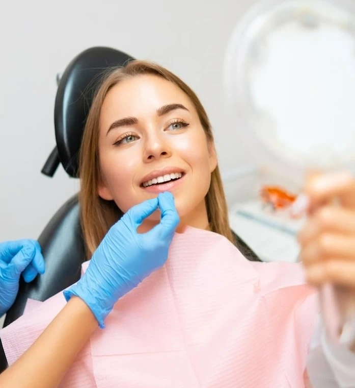 Frau untersucht ihr strahlendes Lächeln beim Zahnarzt